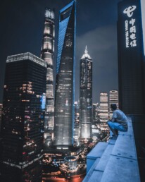guy watching shanghai skyscraper from rooftop