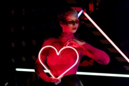 girl with heart shaped red neon light on neon light background