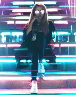 girl seated on stairs with neon light