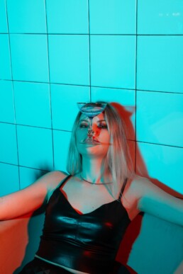 ragazza con top di pelle che tiene un bicchiere da cocktail tra i denti