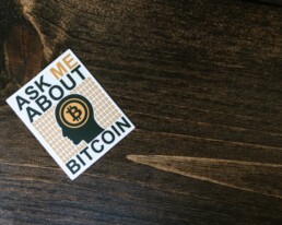 ask me about bitcoin sticker on wooden table