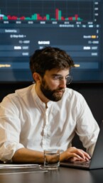 guy with glasses and beard checking crypto market on laptop